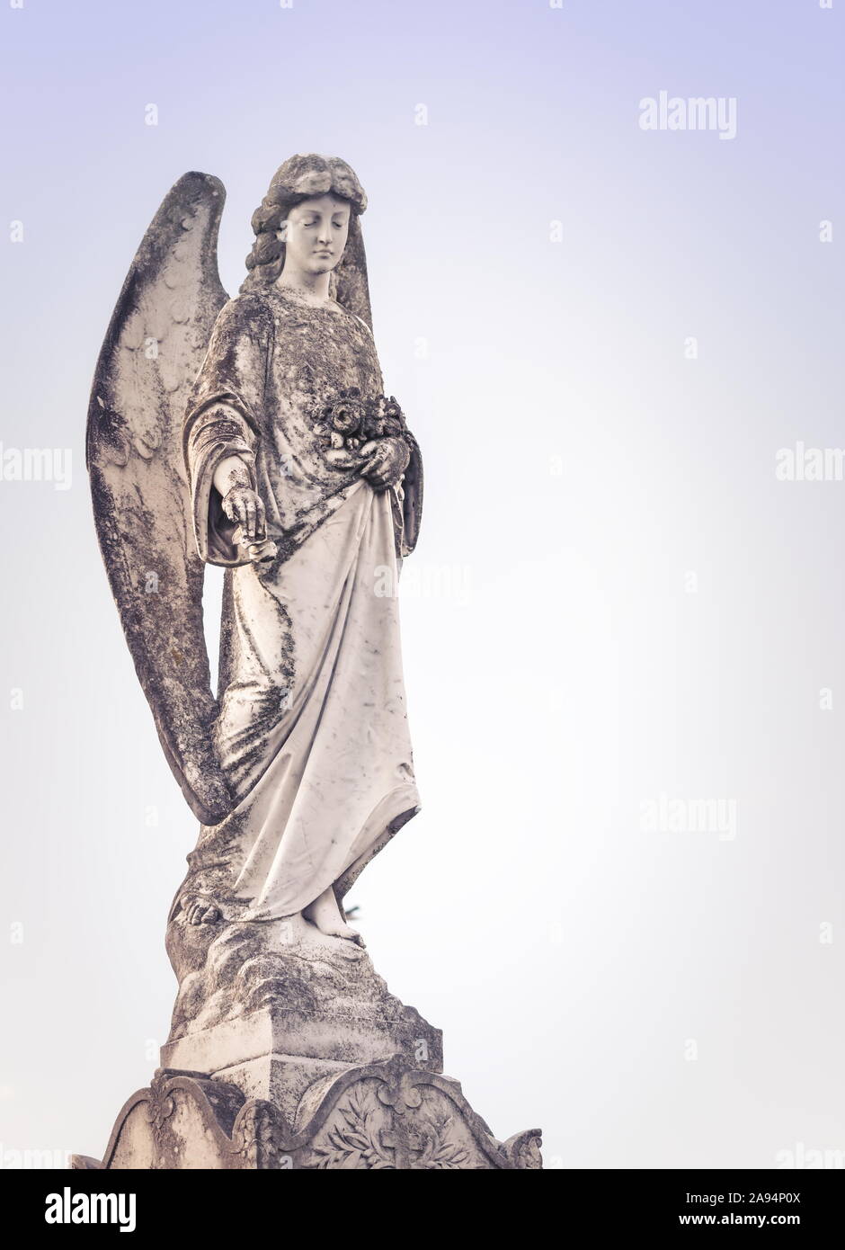 close up image of an angel figurine against a pale sky background. Stock Photo
