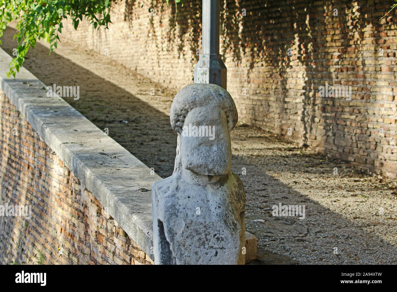 An ancient Roman weather worn or weather-beaten stone statue at the bottom of stone steps leading towards the Villa Borghese park in Rome Stock Photo