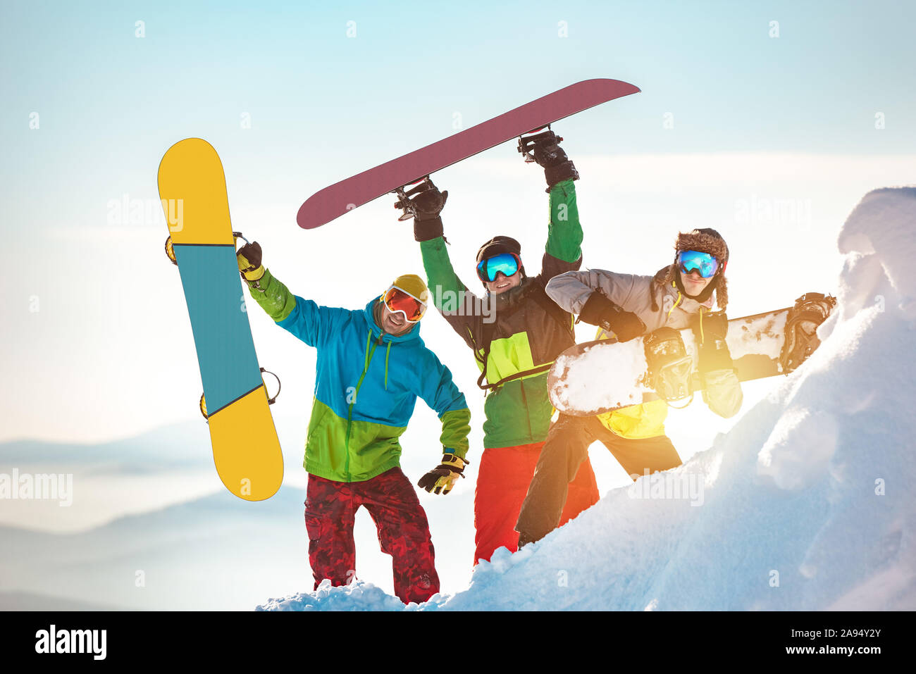 Three happy snowboarders are having fun and posing with snowboards Stock Photo