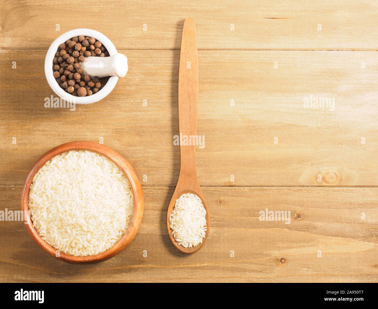 Rice and allspice on brown wooden background. Indian cuisine, ayurveda, naturopathy, modern apothecary concept Stock Photo