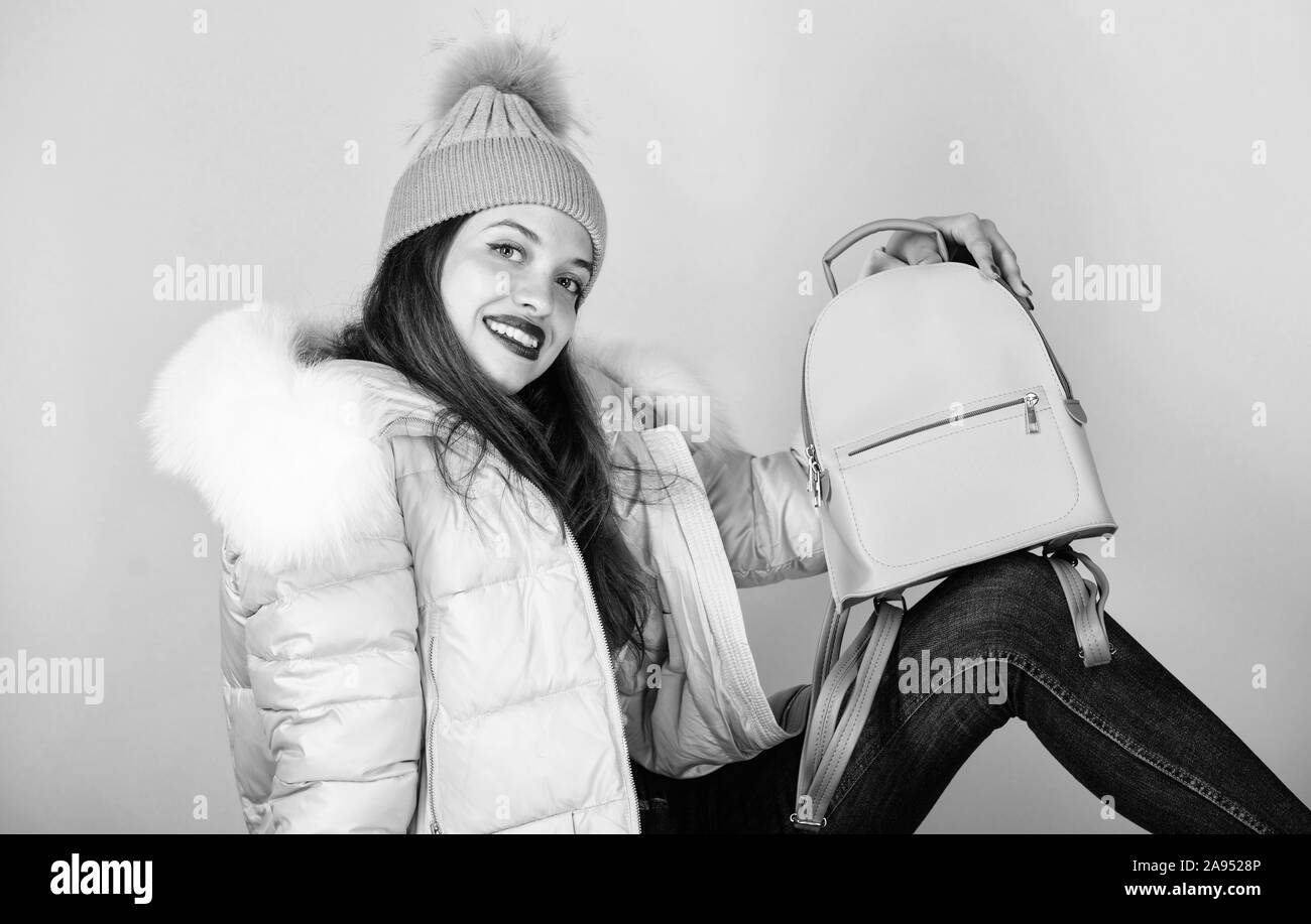 cheerful student. warm winter clothing. shopping. woman in beanie hat with backpack. happy winter holidays. flu and cold season. Leather bag fashion. girl in puffed coat. faux fur fashion. Stock Photo