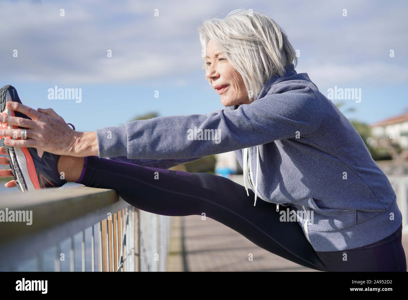 Flexible senior woman stretching outdoors after jog Stock Photo