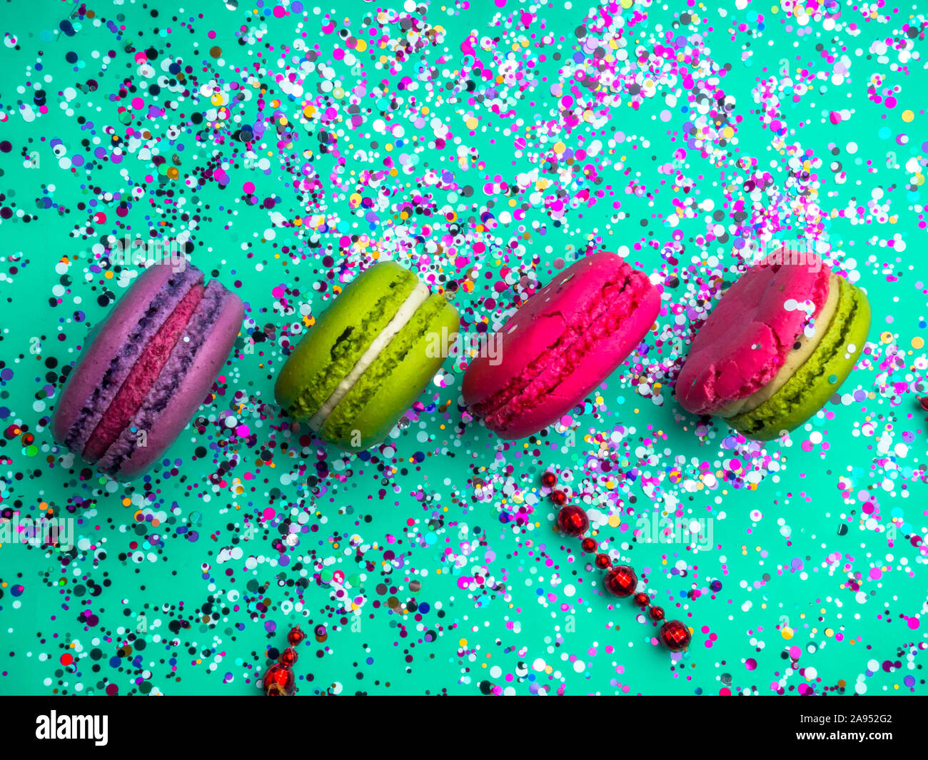 Festive flat lay with colorful confetti and macaroons on trendy mint turquoise background. Holiday concept. Stock Photo