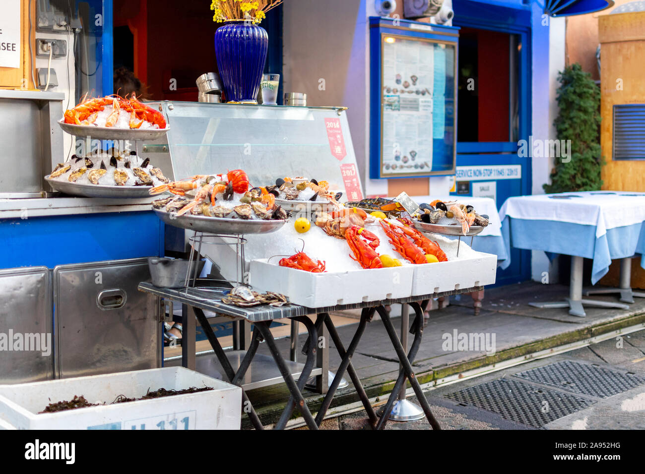 A sidewalk cafe on the Cours Saleya market in Nice, France, displays it's fresh seafood including lobsters in front of the store. Stock Photo