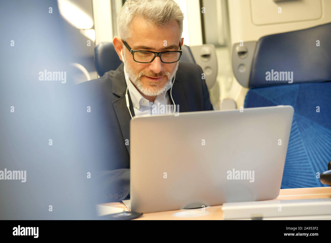 Businessman commuting by train, talking on phone Stock Photo