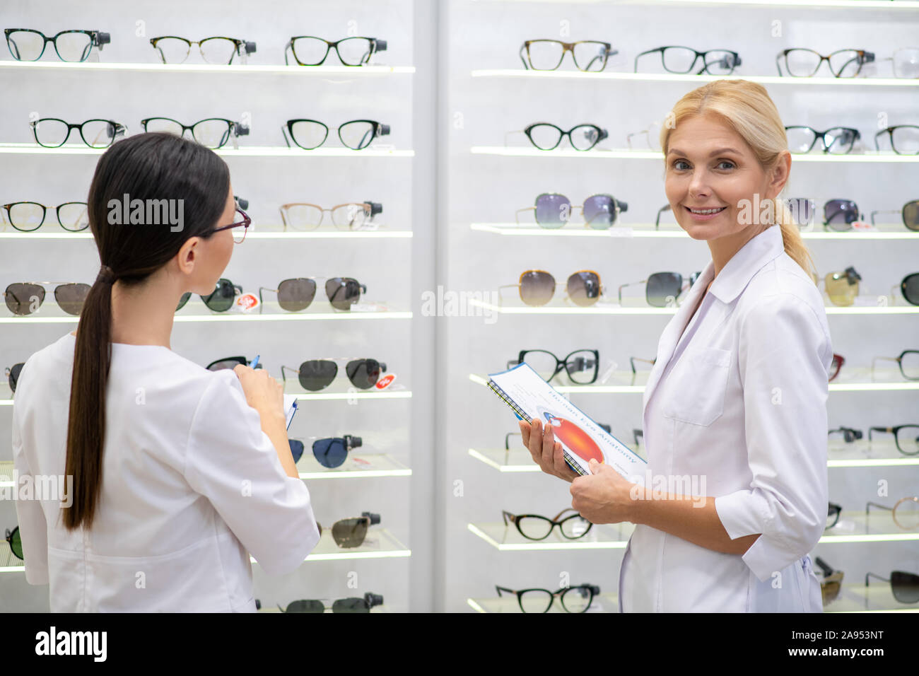 In optical store. Two ophthalmologists wearing white coats working hard