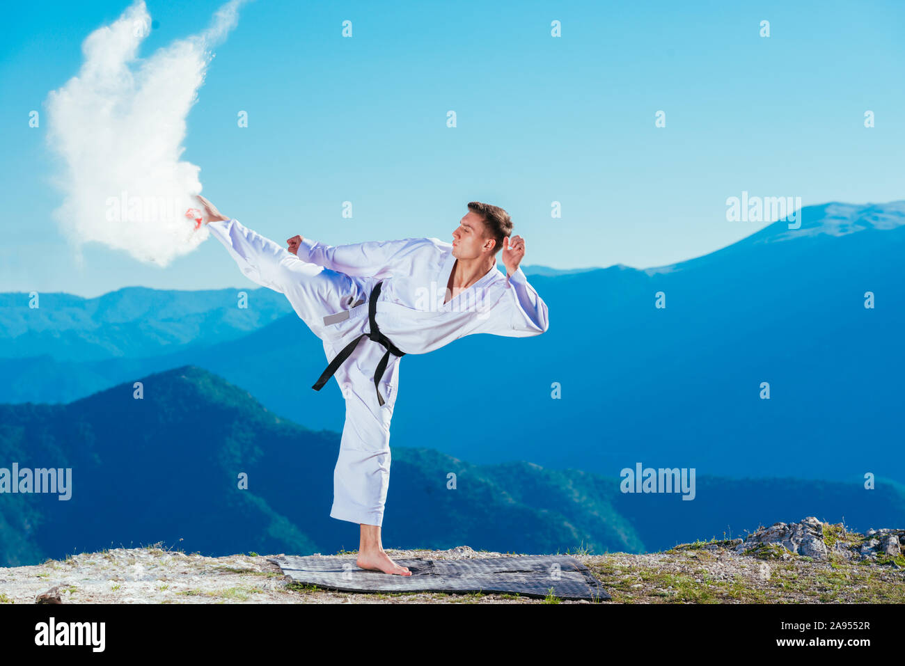 Fit karate athlete kicking a cup filled whit fluor causing a big splash ...