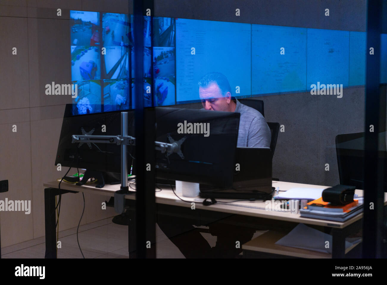 Side view of security system operator using walkie-talkie while looking at CCTV footage Stock Photo