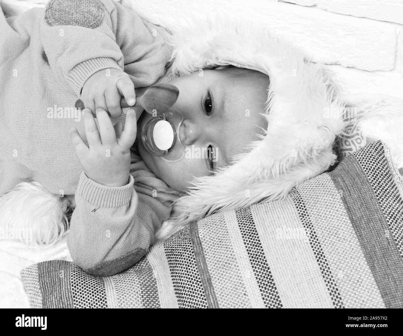 small baby boy with adorable curious face in yellow sweater laying with