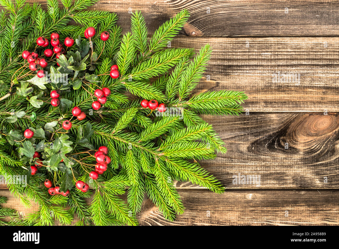Christmas fir tree with red berries on rustic wooden background Stock ...