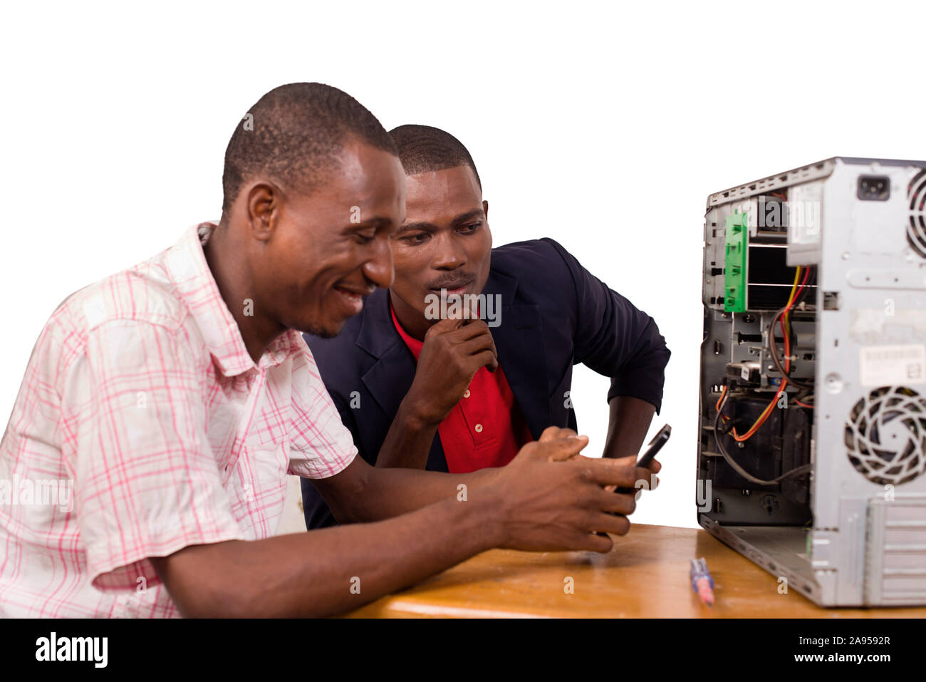 two technicians sitting at the desk working together on a computer Stock Photo