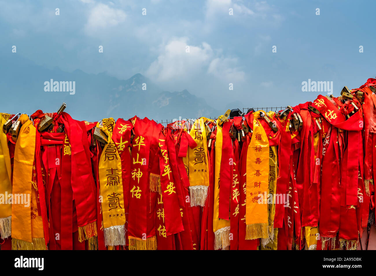 Huashan, China -  August 2019 : Red and yellow ribbons attached to the protective barrier on a lookout with the stunning mountain landscape view from Stock Photo