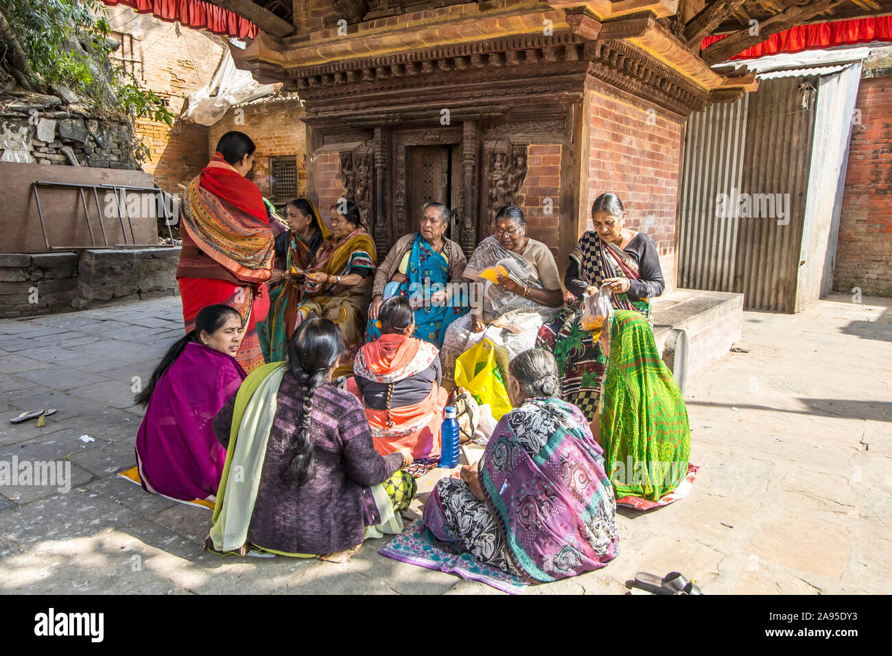 A group of Hindu women devotees in colorful sarees chanting prayers inside the Kathmandu Durbar Square in front of the main temple Stock Photo