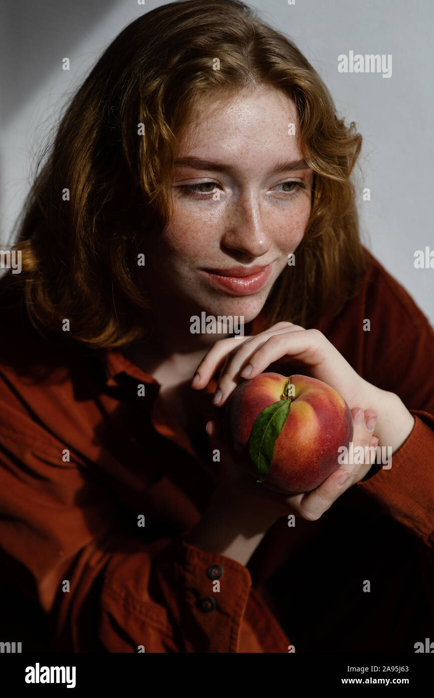 Portrait Of Beautiful Smiling Woman With Long Red Hair Holding