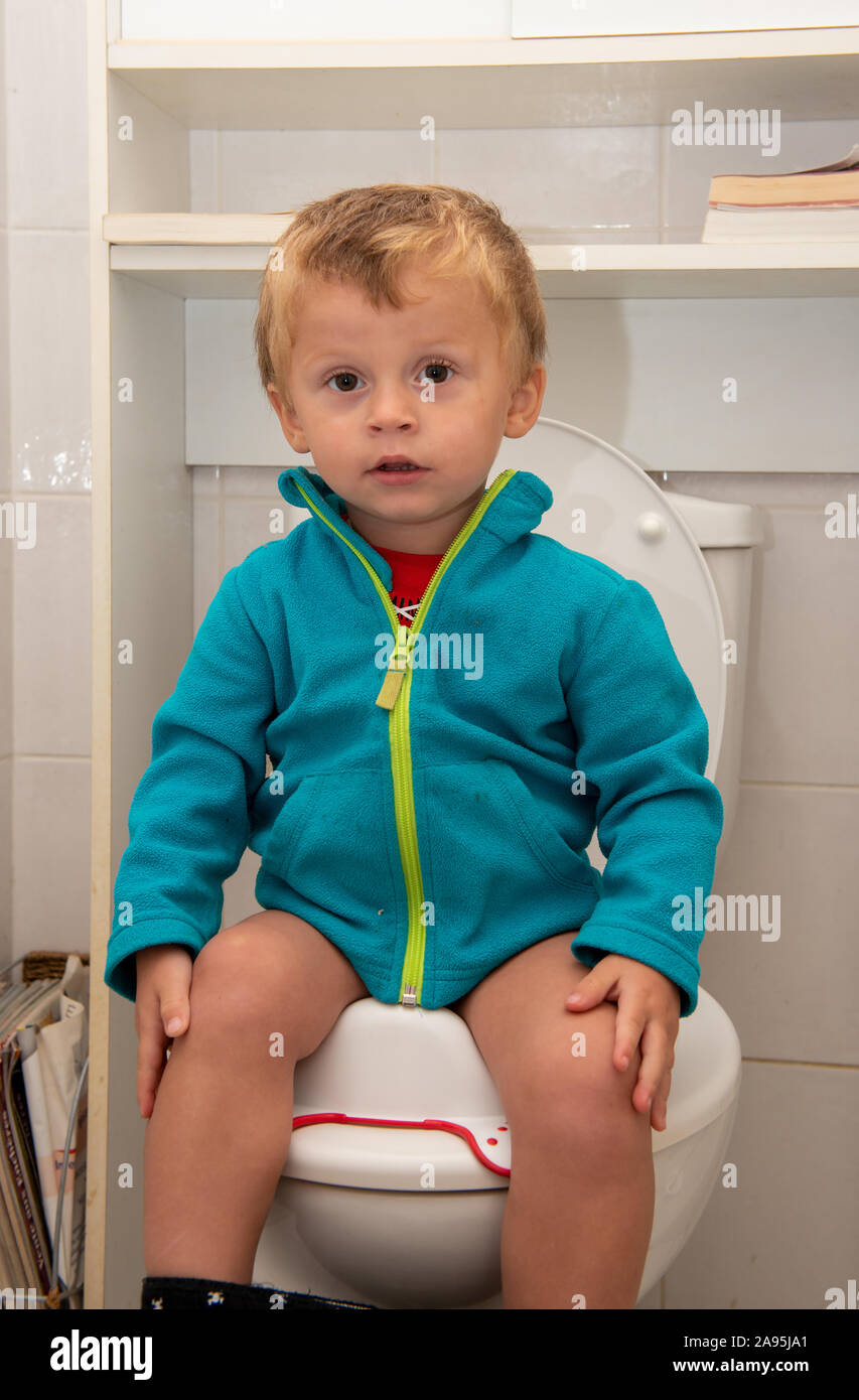 a cute little toddler baby child sitting on toilet wc Stock Photo