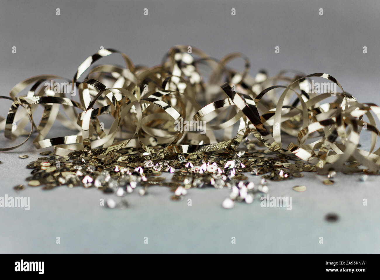 Golden sequins and metallic ribbon on neutral grey background. Copy space. Luxury celebration. Stock Photo