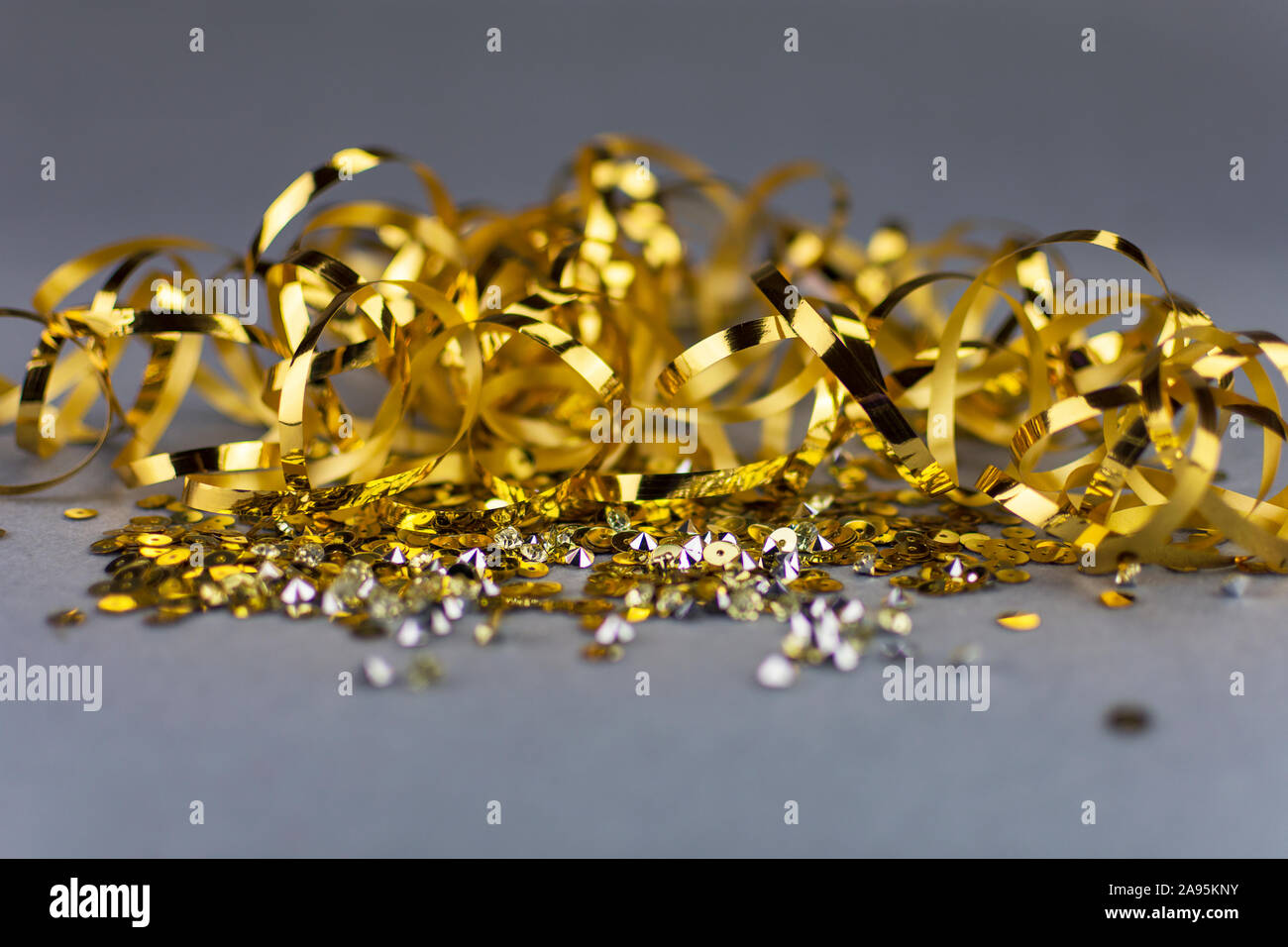 Golden sequins and metallic ribbon on neutral grey background. Copy space. Luxury celebration. Stock Photo