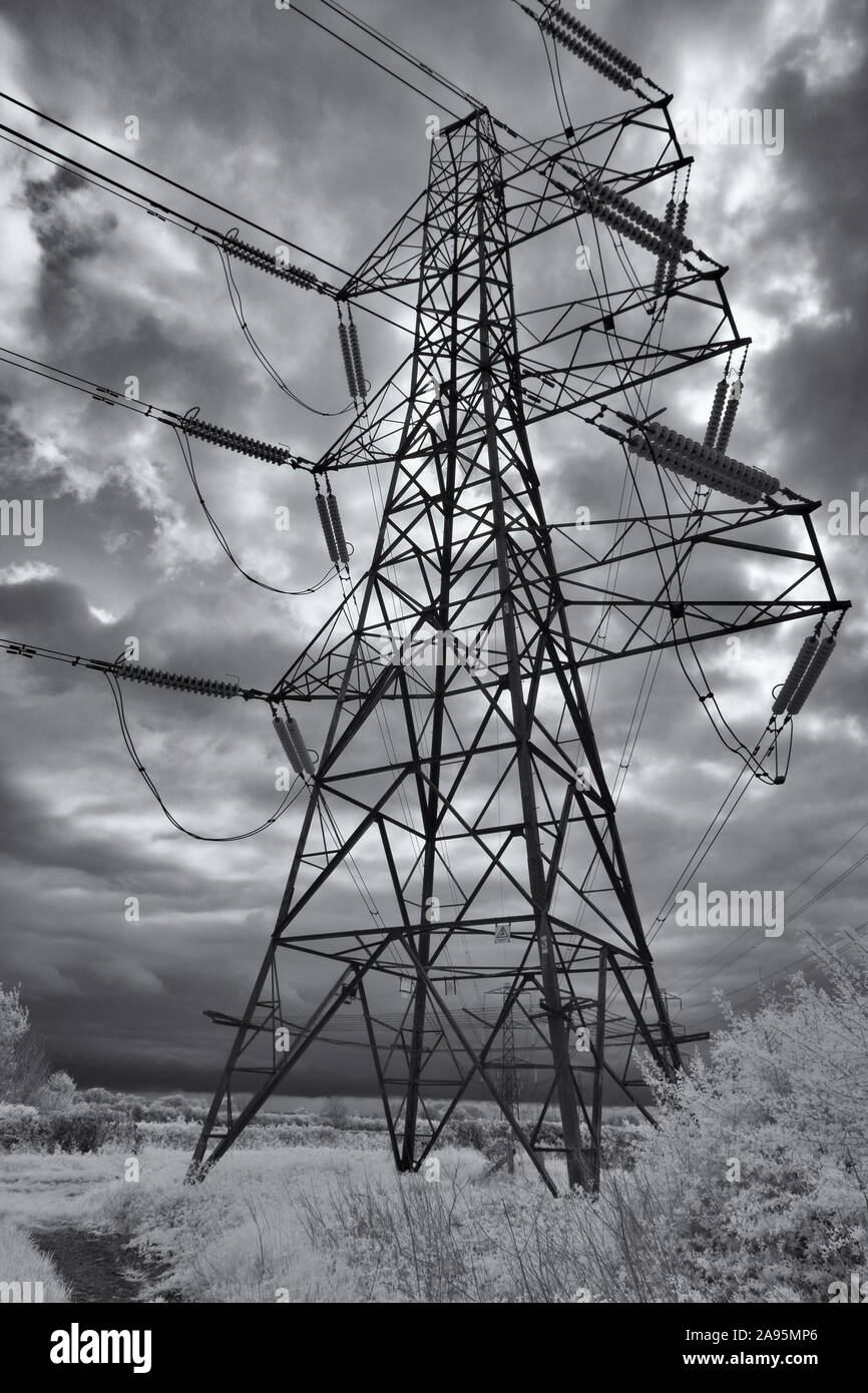 Black and white (infrared) image of mains electricity pylons under an angry sky near Cirencester Stock Photo