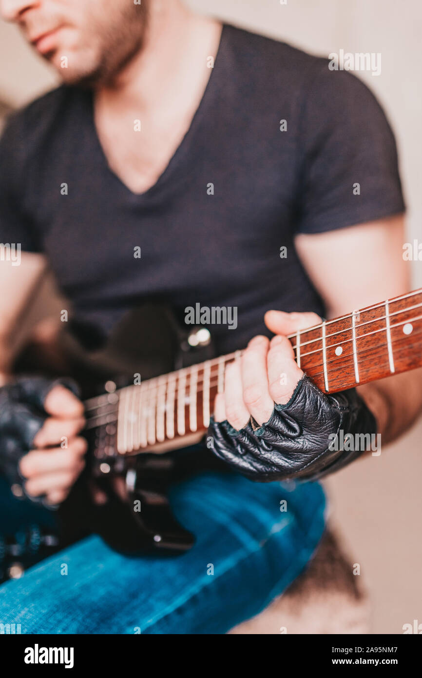 Rocker in black T-shirts and jeans playing hard rock on a black electric guitar Stock Photo