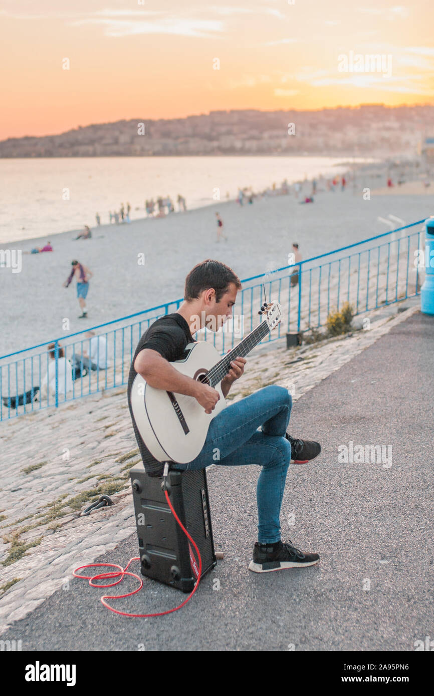 Nice, Provence / France - September 28, 2018: Street musician with a white guitar on the boardwalk Stock Photo