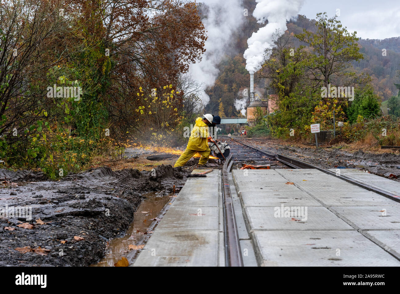Men working to repair railroad tracks with mountain background. Stock Photo