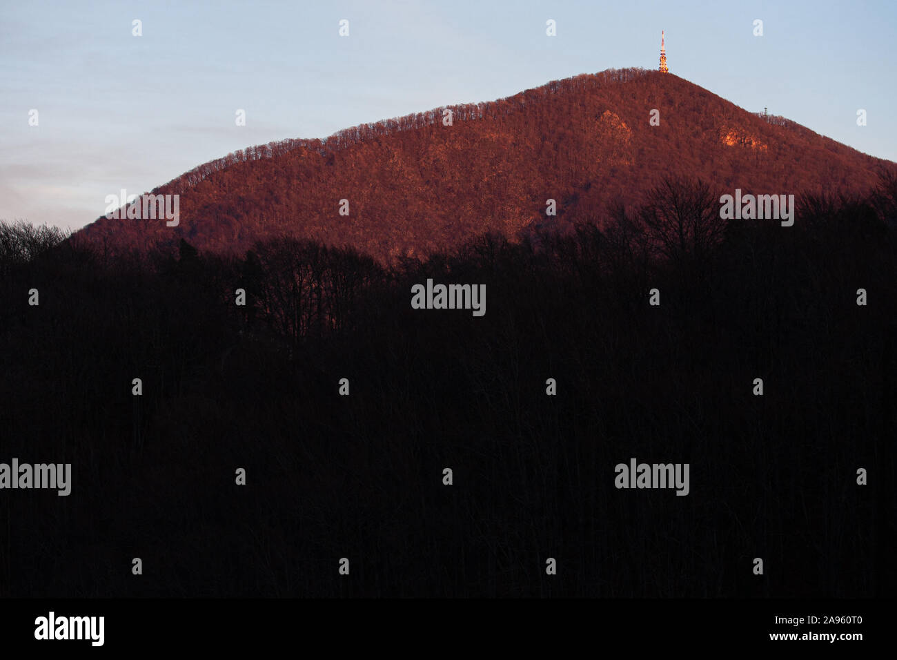 A mountain with a transmitter on its peak at sunset. Stock Photo