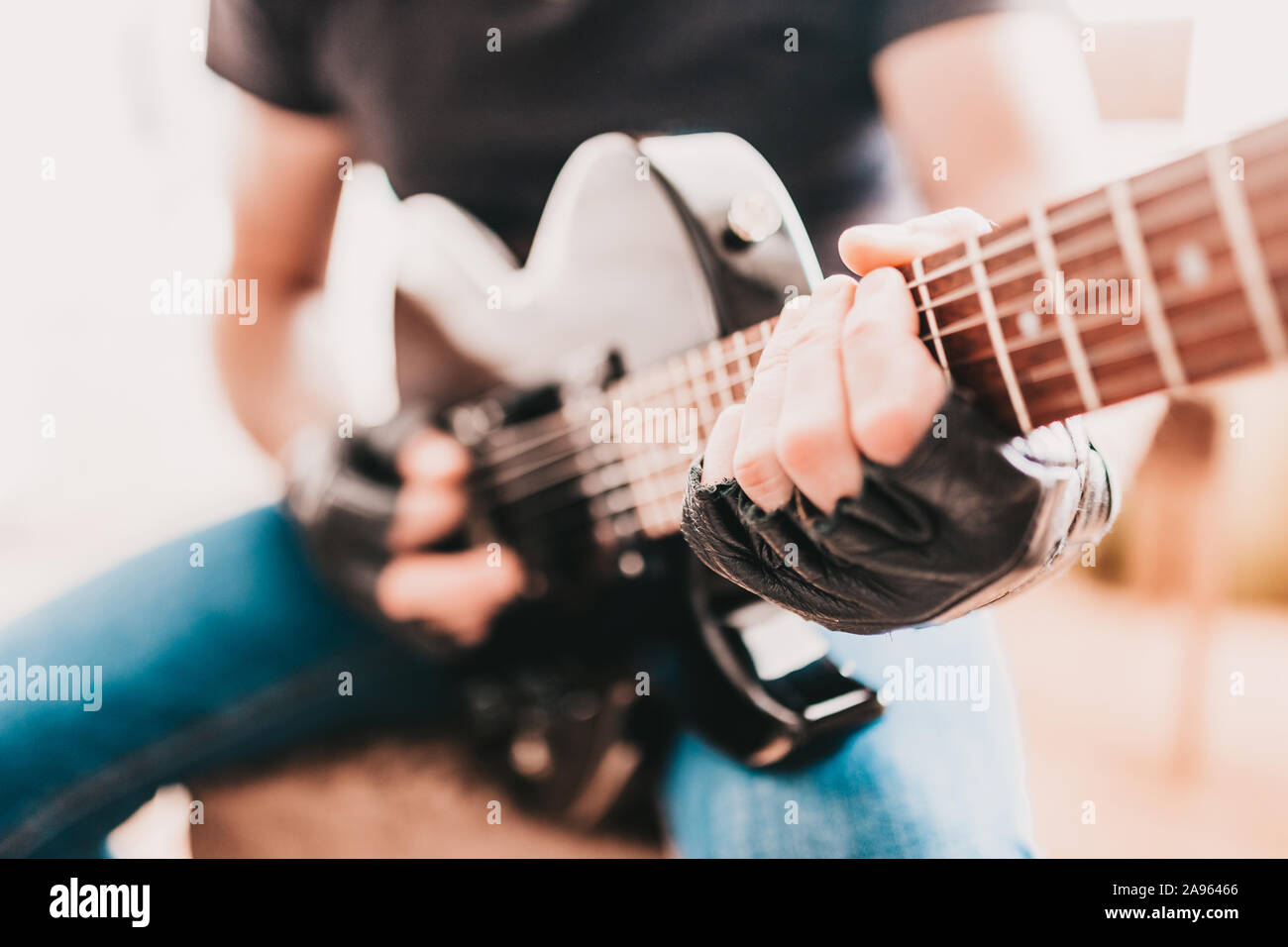 Rocker in black T-shirts and jeans playing hard rock on a black electric guitar Stock Photo