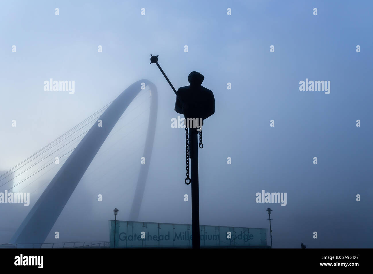 NEWCASTLE UPON TYNE, UK - NOVEMBER 09 2019: River God sculpture, by Andre Wallace, shrouded in fog with Gateshead Millennium Bridge in the background at the Quayside, Newcastle, UK Stock Photo