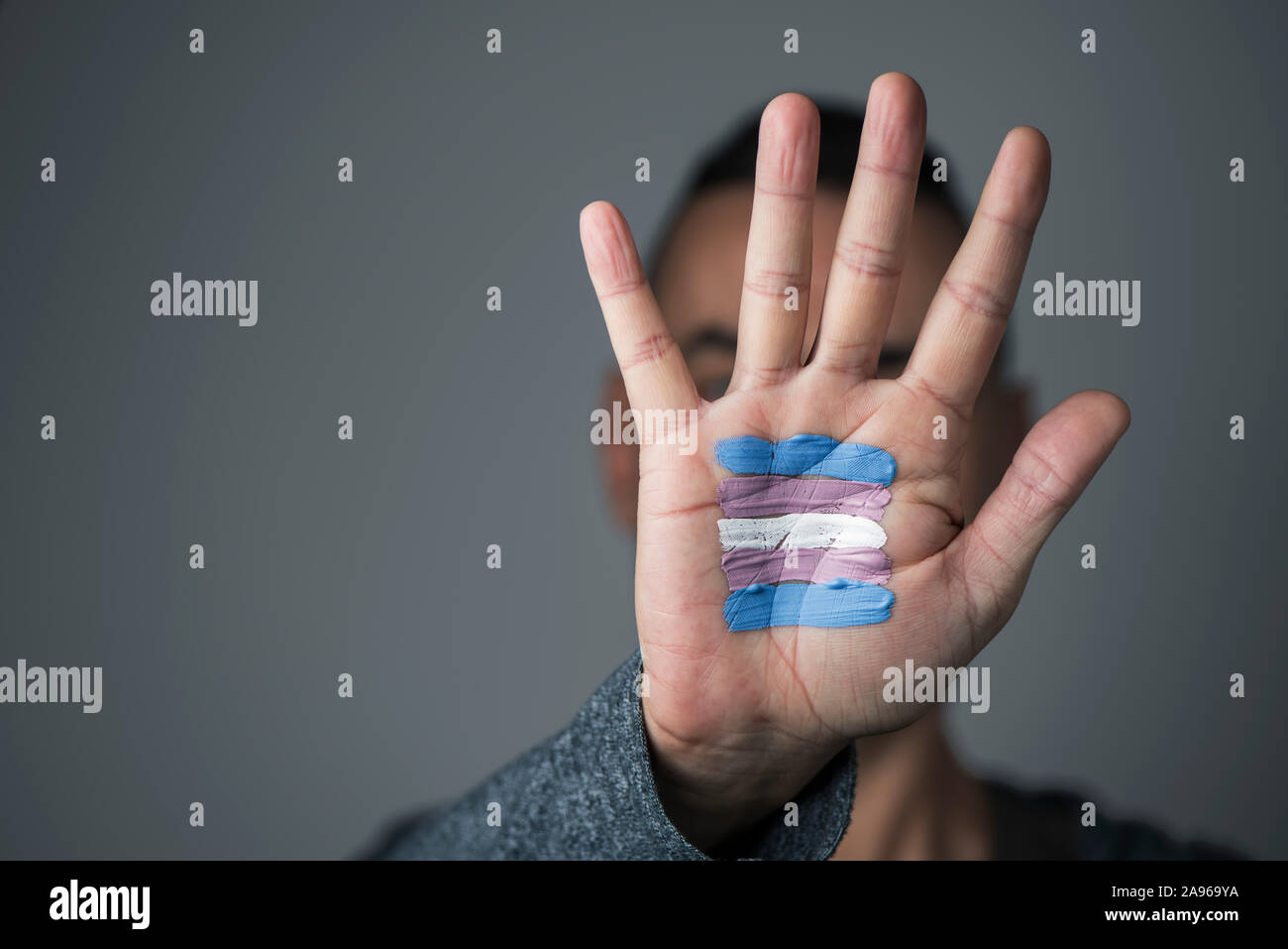 closeup of the palm of the hand of a young caucasian person with a transgender flag painted in it, in front of his or her face Stock Photo