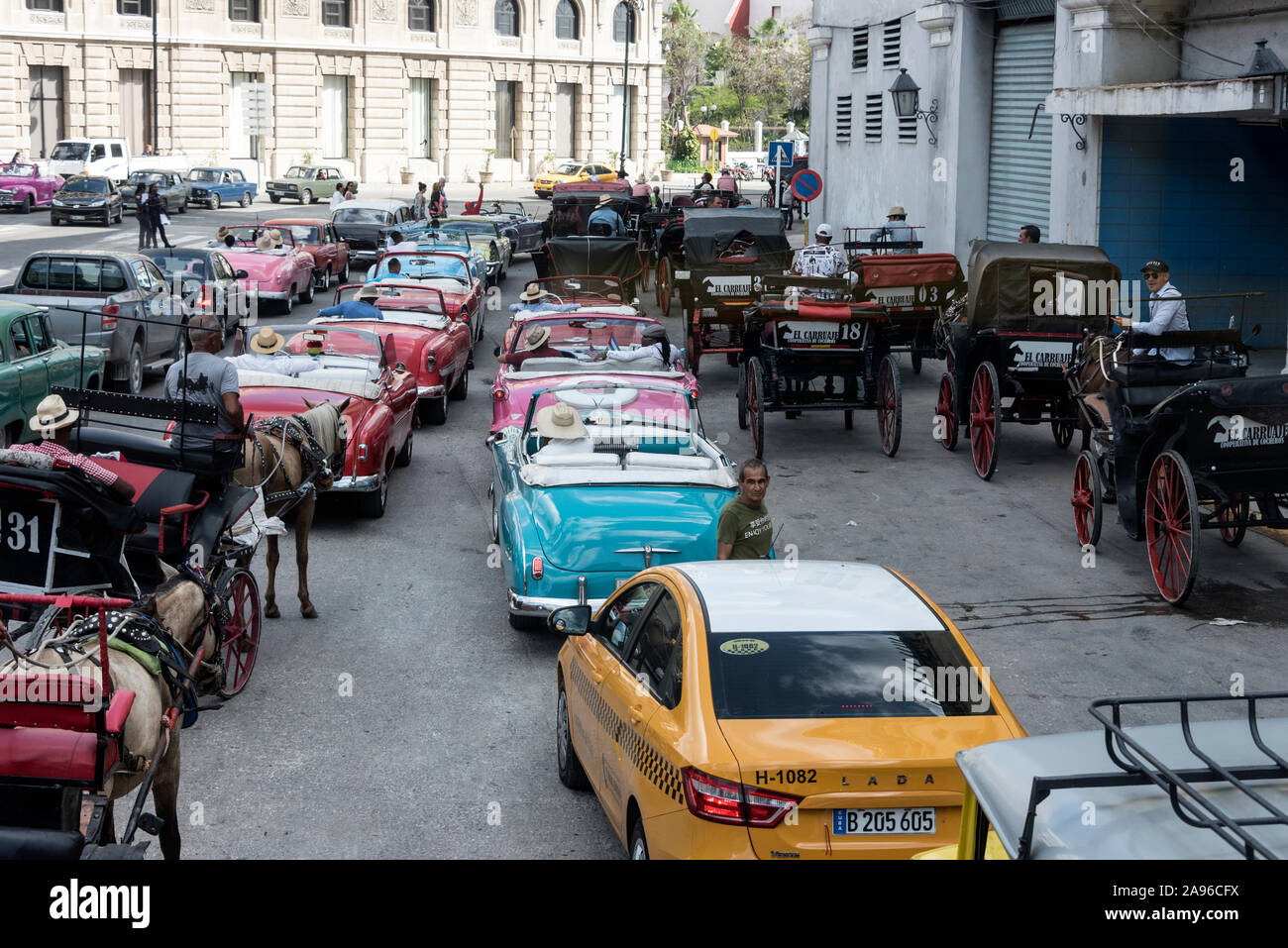 A fleet of American classic cars, horse drawn carriages, and a yellow city taxi,  waiting for cruise ship passengers at the Terminal Sierra Maestra ne Stock Photo