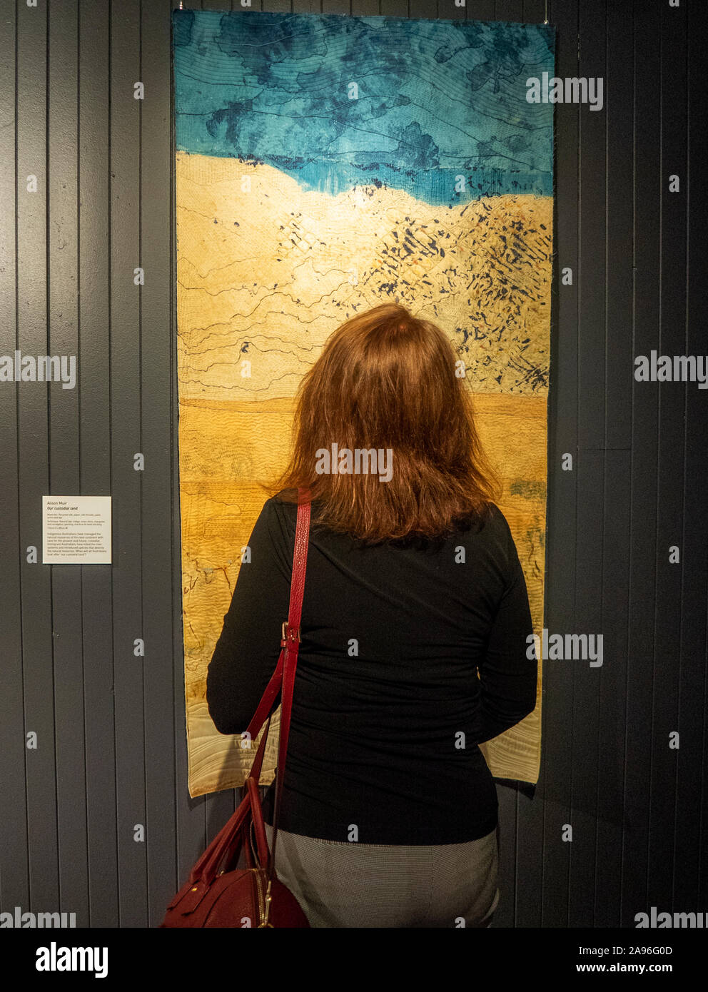 Woman looking atuilt Our Custodial Land by quilter Alison Muir on display at Art Quilt Australia