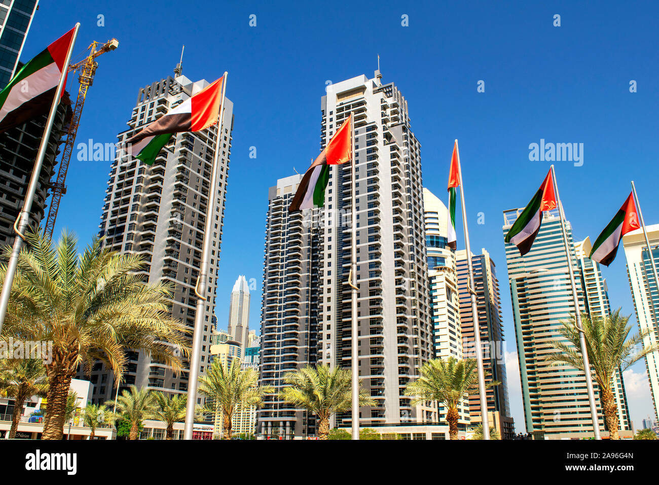 Dubai / UAE - November 11, 2019: View of JLT skyscrapers with UAE flags. United Arab Emirates flags waving on blue sky background. National day. Group Stock Photo