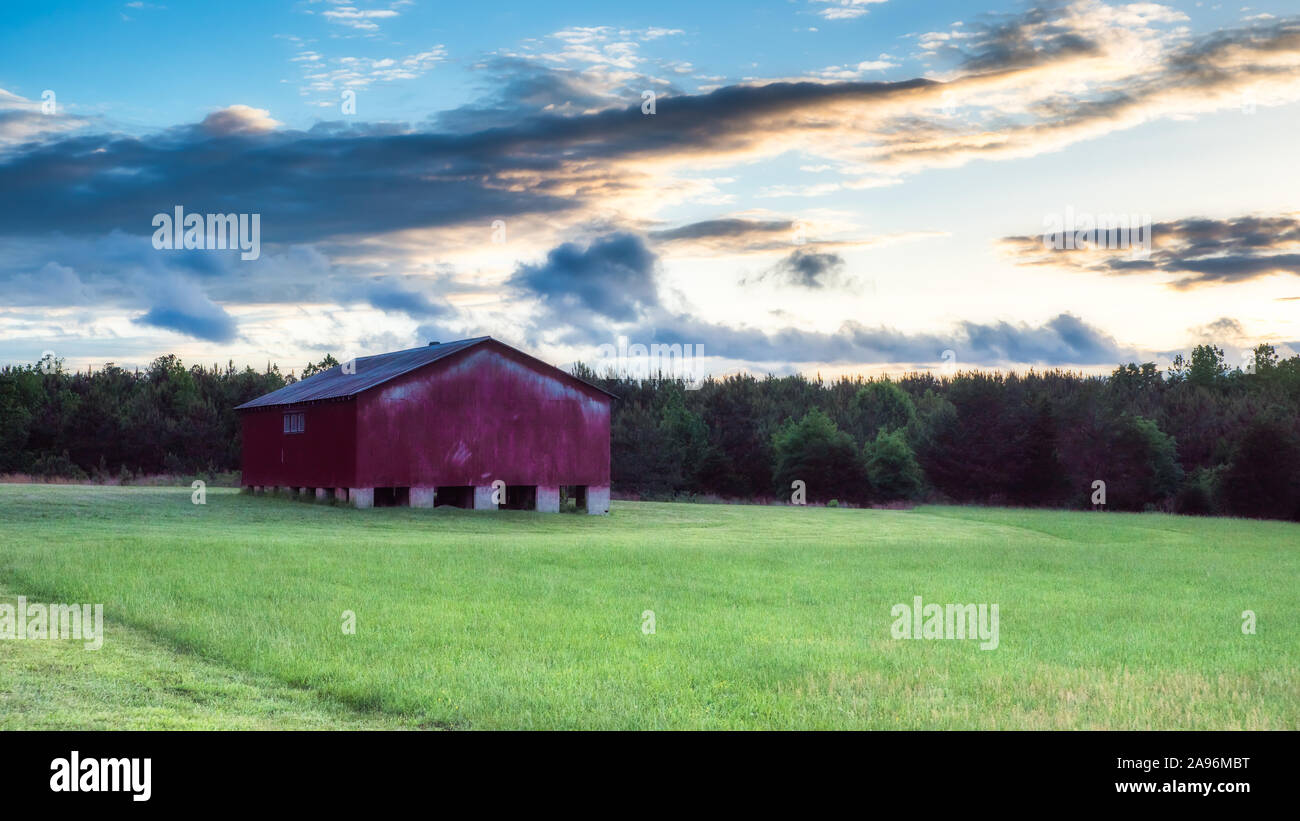 Red barn in a green field with blue sky and clouds in the background ...