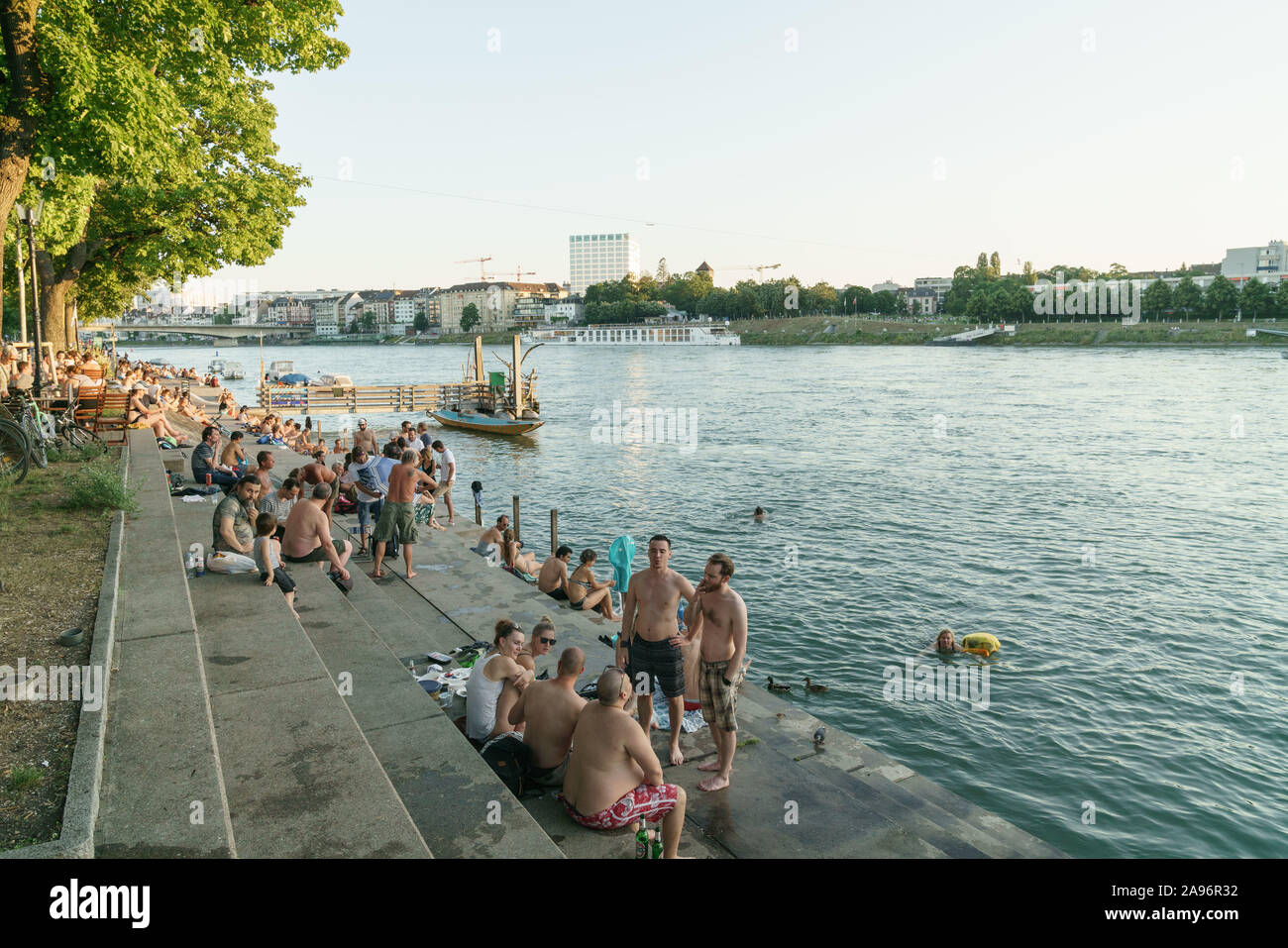 People sitting by the river Rhine in Basel Stock Photo
