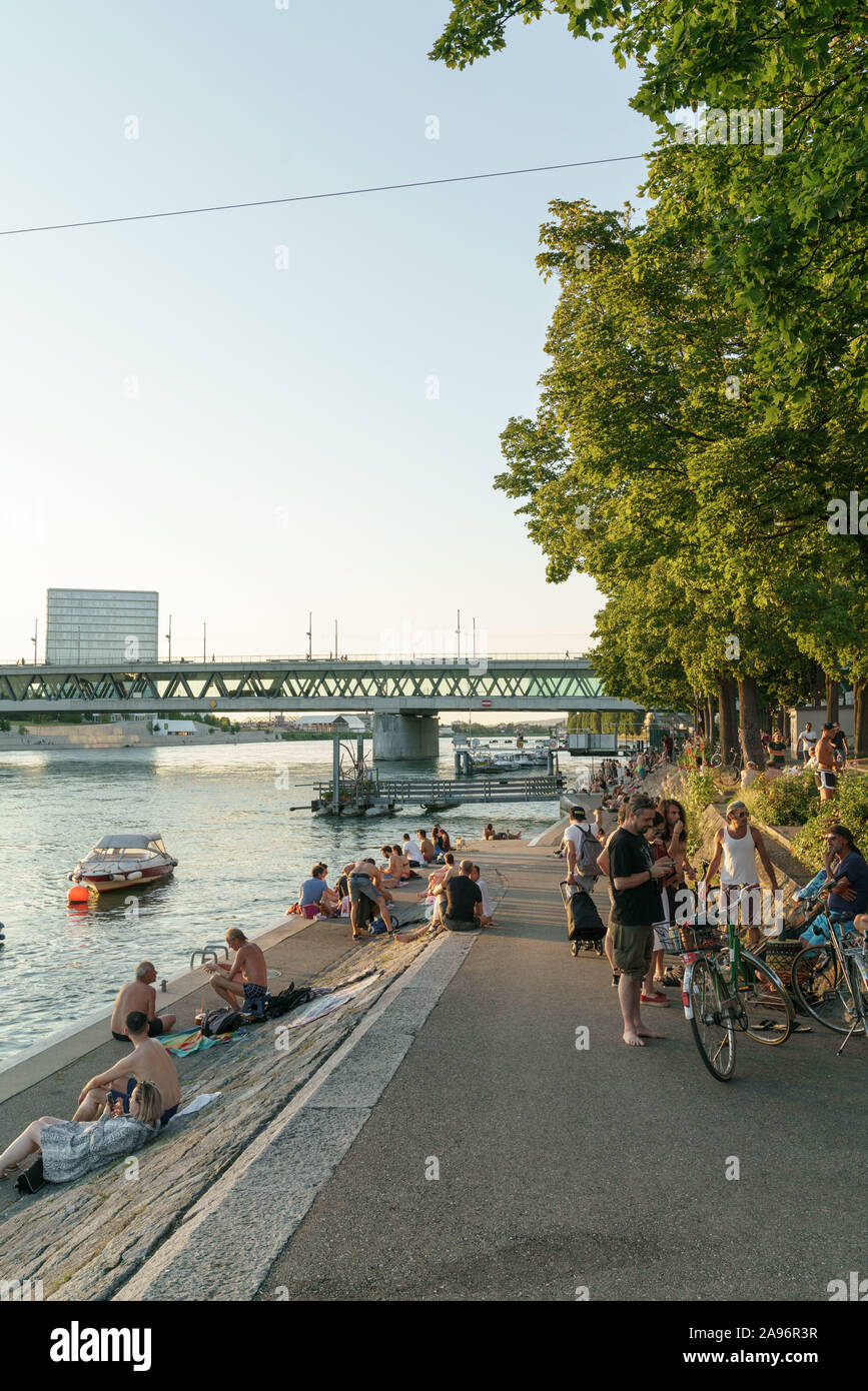 People sitting by the river Rhine in Basel Stock Photo
