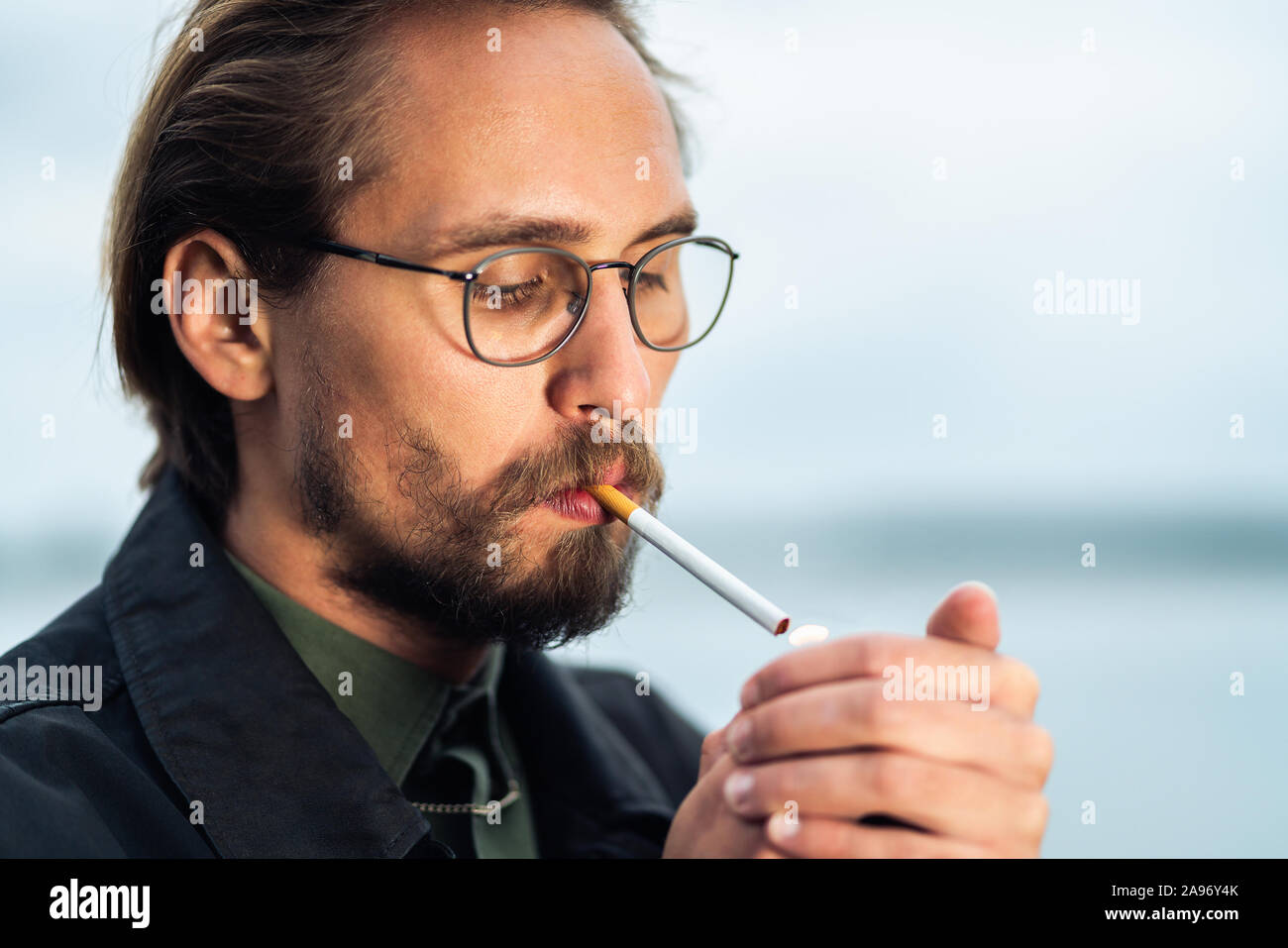 Photo of a young man lighting up a cigarrete Stock Photo