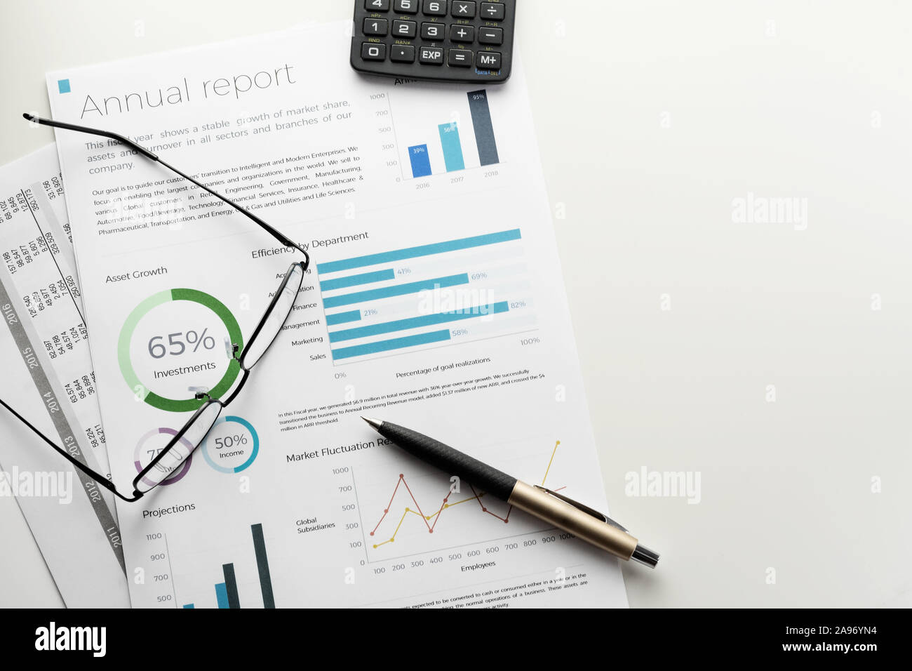 Mockup annual report sheet with charts and graphs, pen, calculator and
