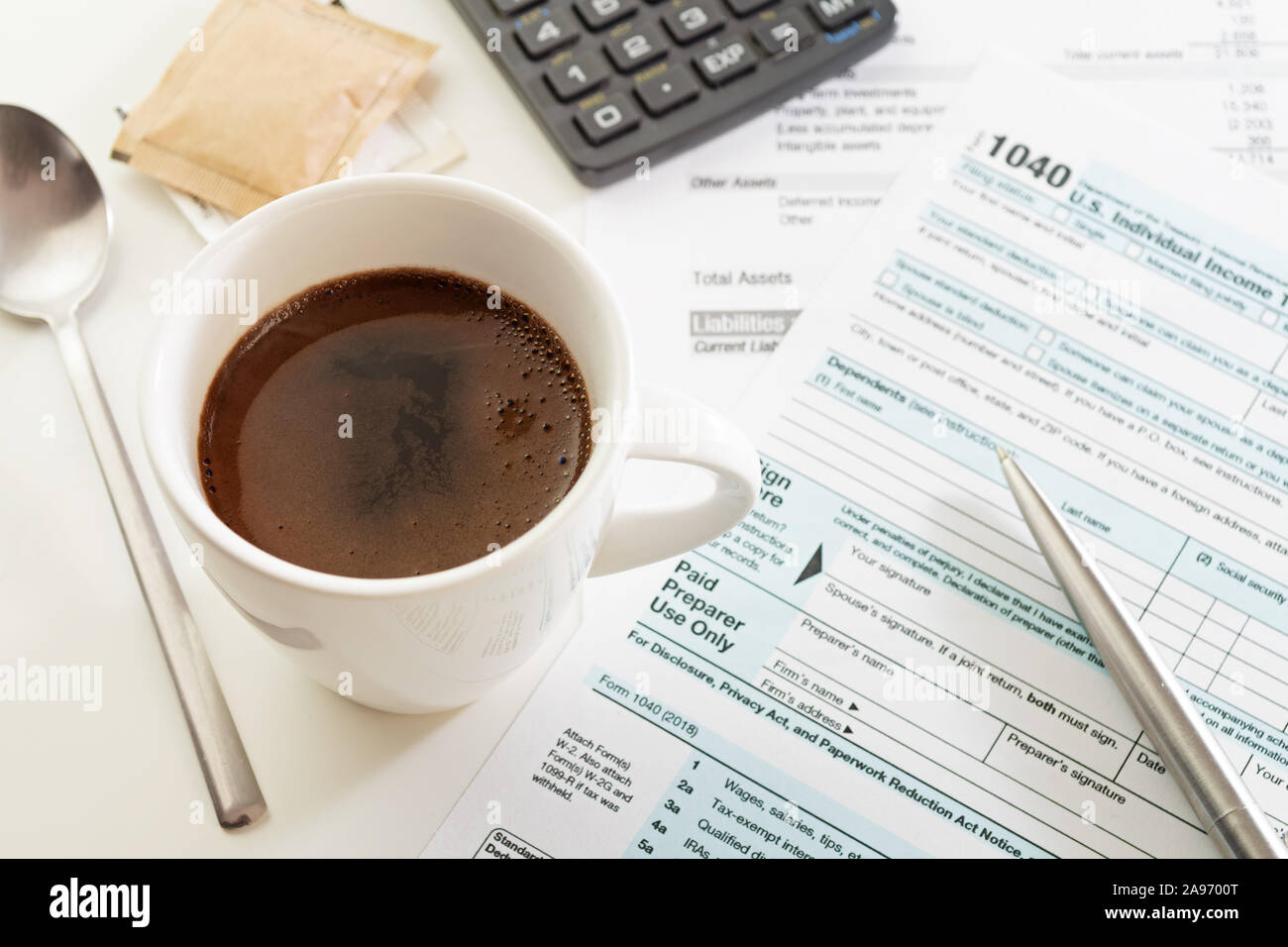 Cup of espresso on white table with U.S. income tax return form 1040, pen, calculator spoon and sugar. Tax, accounting, finance and taking a break Stock Photo