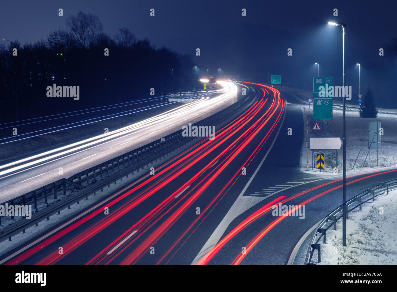 Highway at night with bright trails of light from incoming and outgoing ...