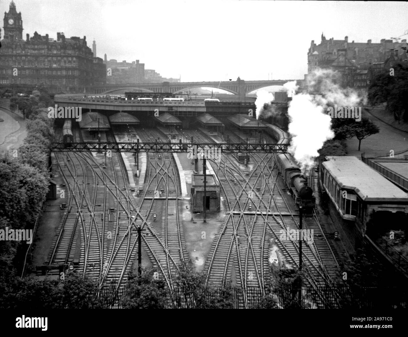 A steam train leaves Edinburgh station in the 1940s. A high angle view showing all the rail lines and the North British Station Hotel in the distance Stock Photo