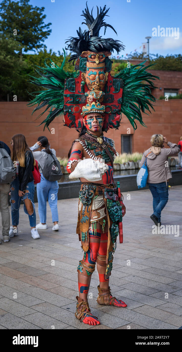 Liverpool, Merseyside, Uk - August 2 2018: Man in Aztec costume poses in the street with members of the public in Liverpool. Stock Photo