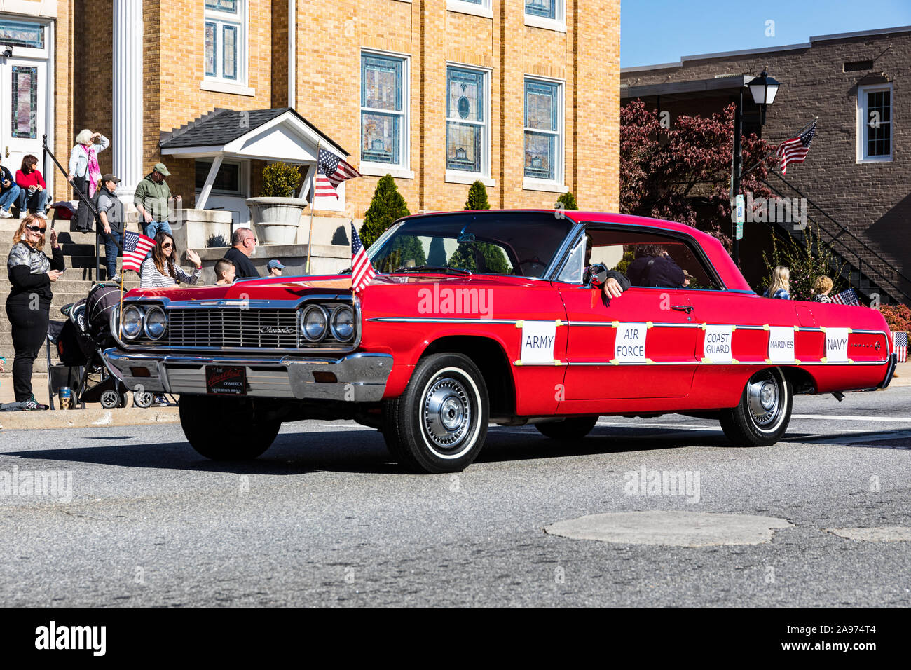 LINCOLNTON, NC, USA-11 NOV 2019: Red 1964 Chevrolet Impala driven in veterans' parade, with printed signs saying: 'Army', 'Air Force', 'Coast Guard' Stock Photo