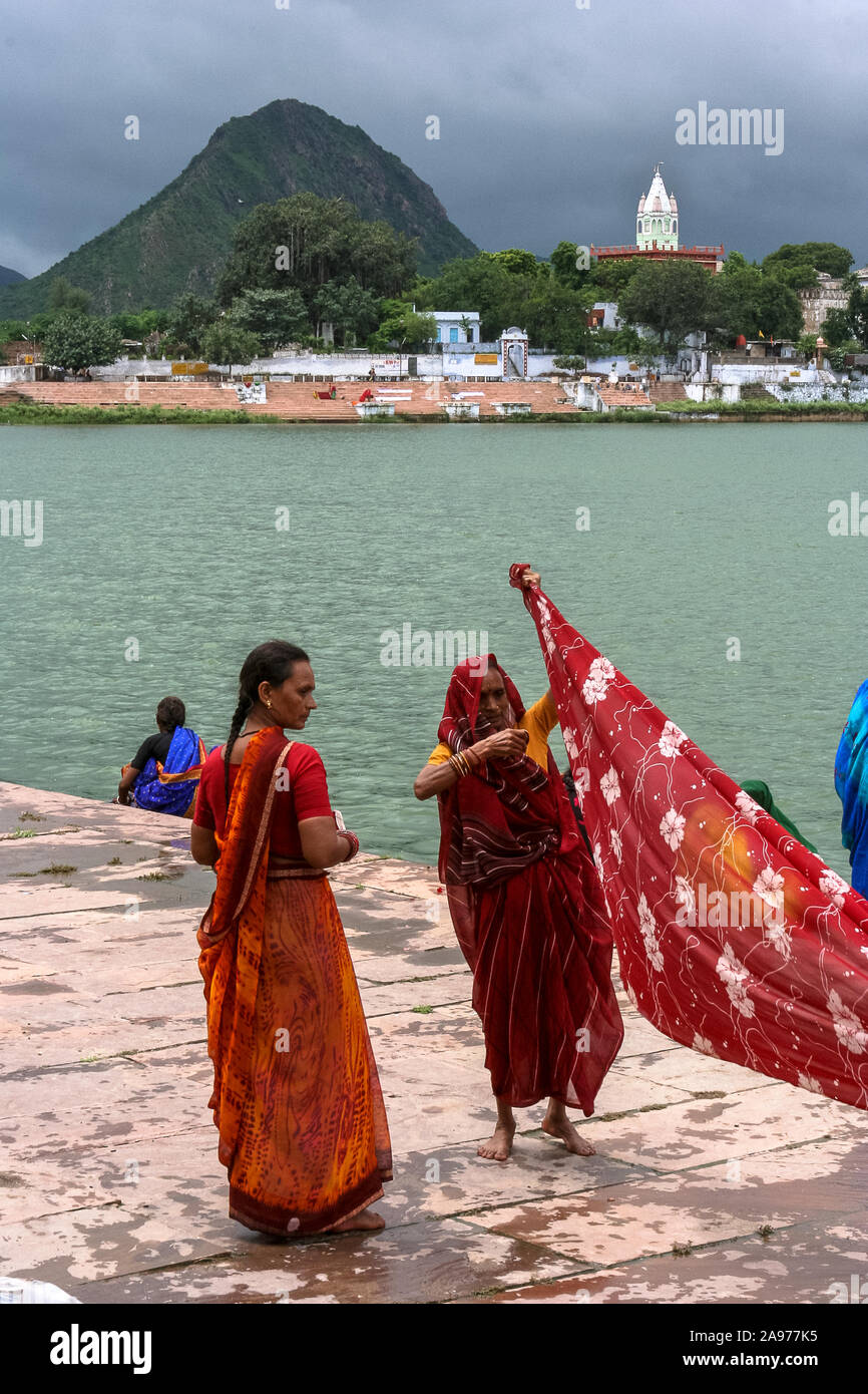 Pushkar, Rajasthan, India: two Indian women blow wet saris on the shores (ghat) of the holy Pushkar lake Stock Photo