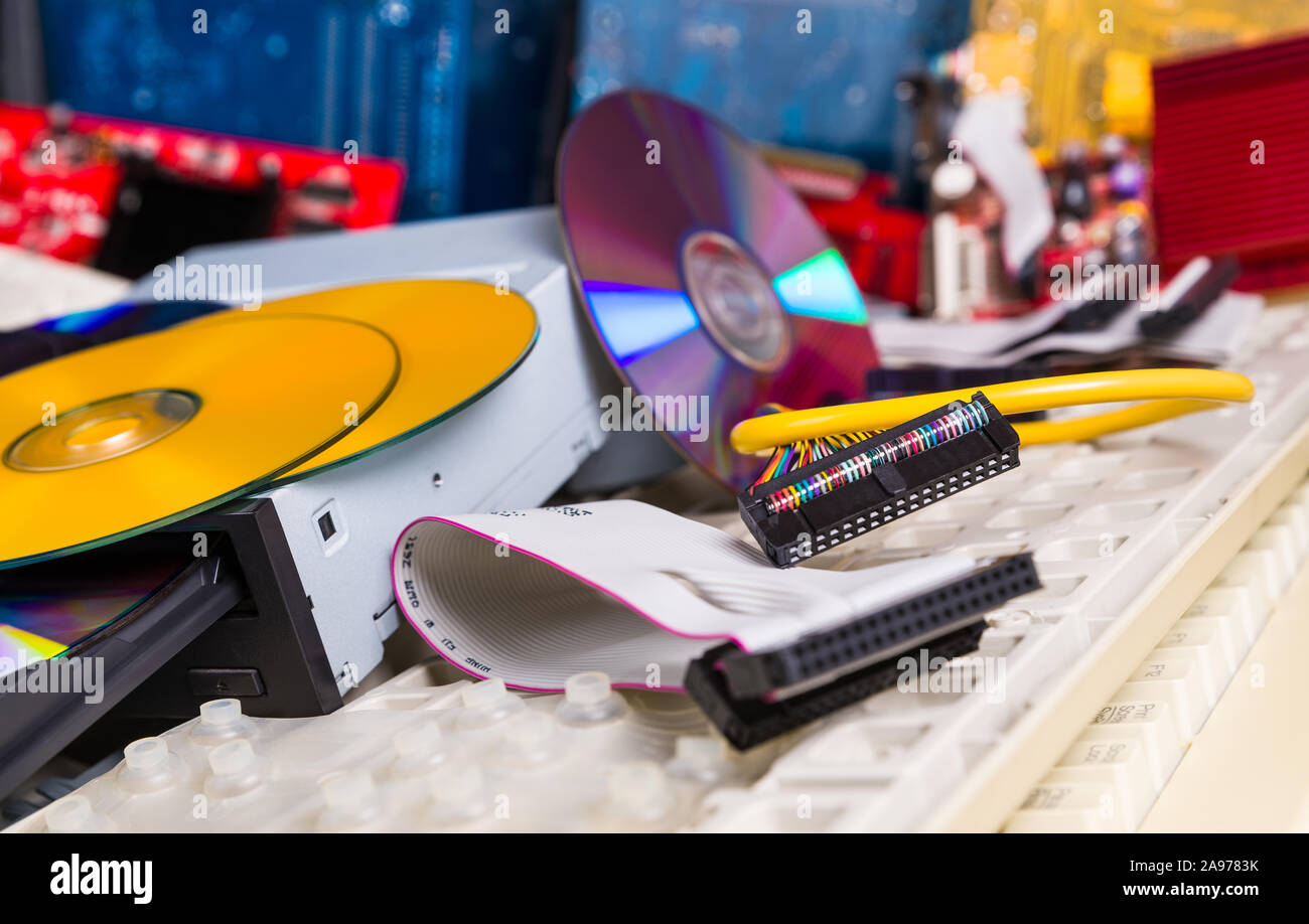 Used computer hardware components. E-waste pile detail. Discarded spare PC parts and accessories as compact discs, keyboards, hard disk drive, cables. Stock Photo