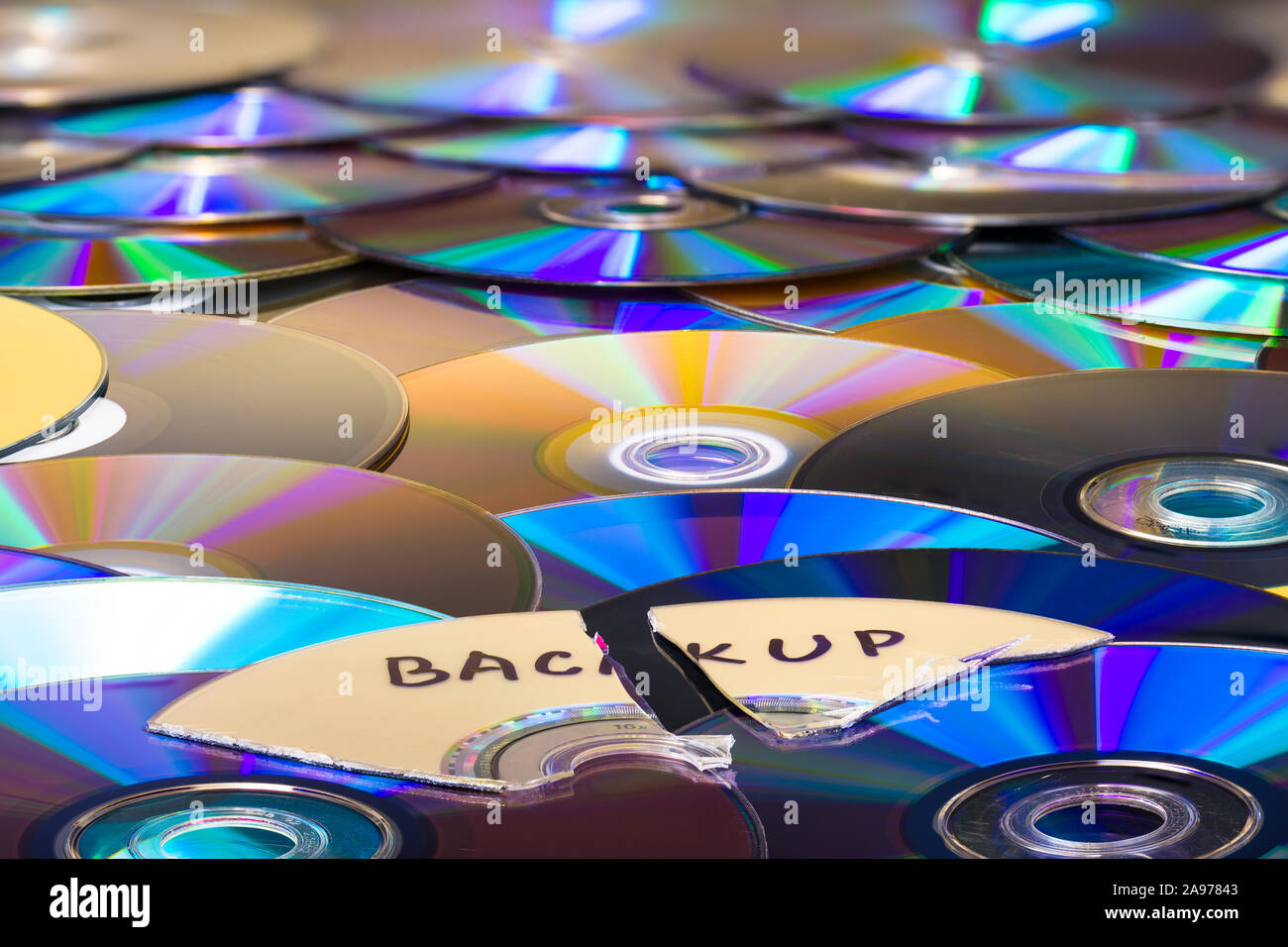 Shredded optical compact disc parts on heap of colored archiving media. Obsolete data storage device for secure backup. Secret digital files disposal. Stock Photo