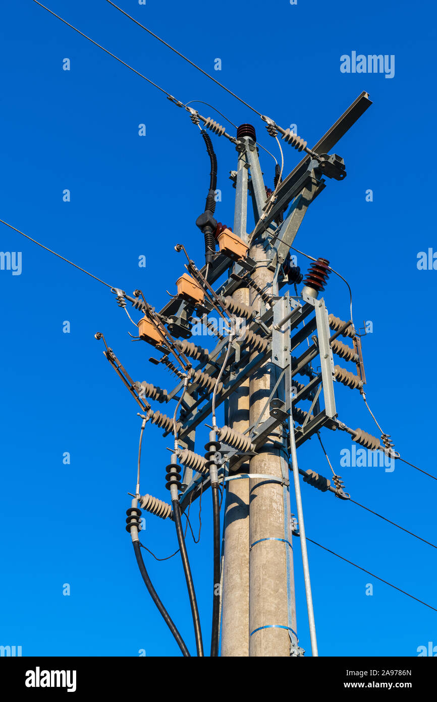 Medium voltage disconnectors on electricity pole with isolator switches used to disconnect of electric circuit for safe service, maintenance or repair. Stock Photo