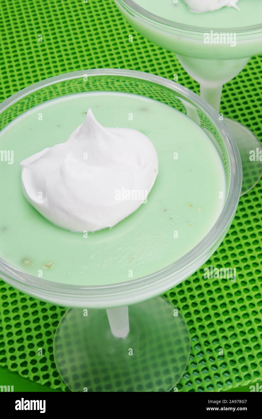 Overhead shot of homemade green colored pistachio pudding with a dollop of whipped cream on top served in two frosted margarita glasses. Naturally lit Stock Photo