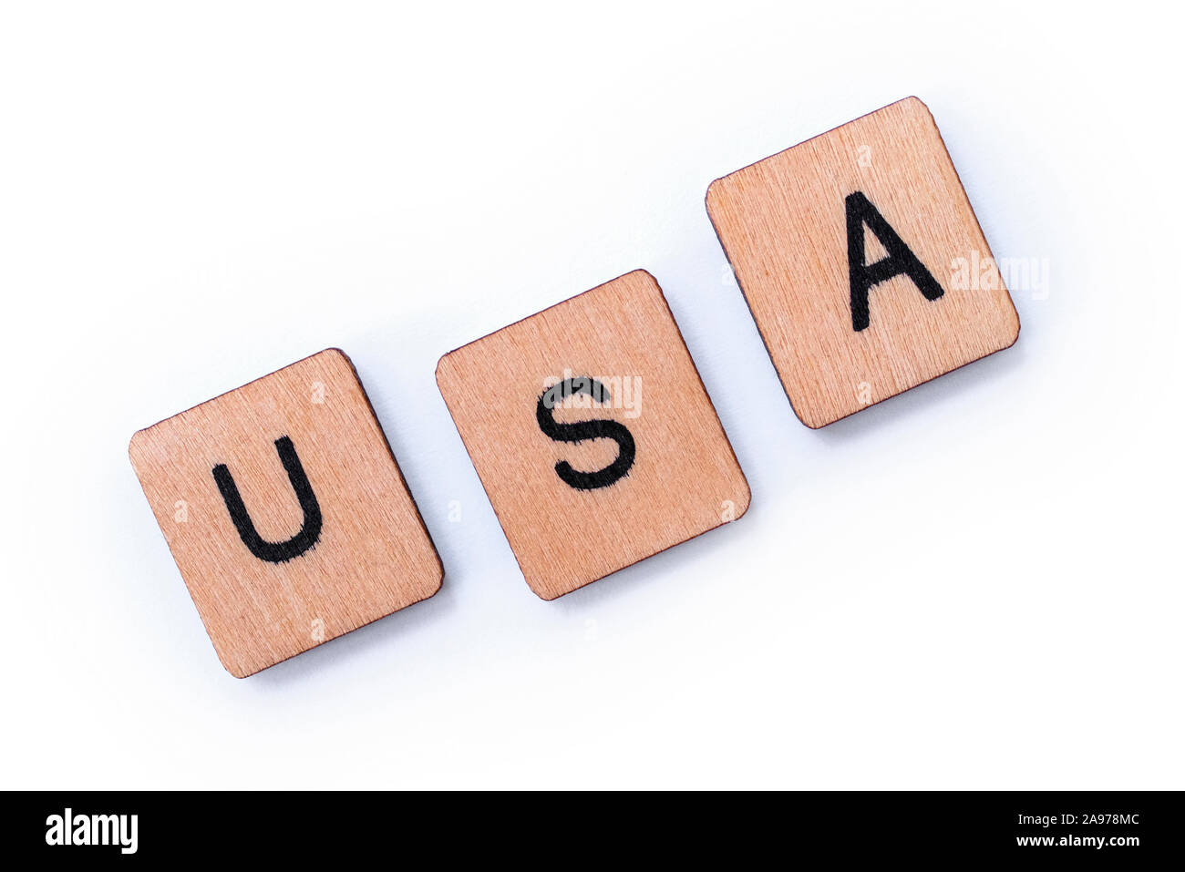 The abbreviation USA - standing for the United States of America, spelt with wooden letter tiles over a white background. Stock Photo