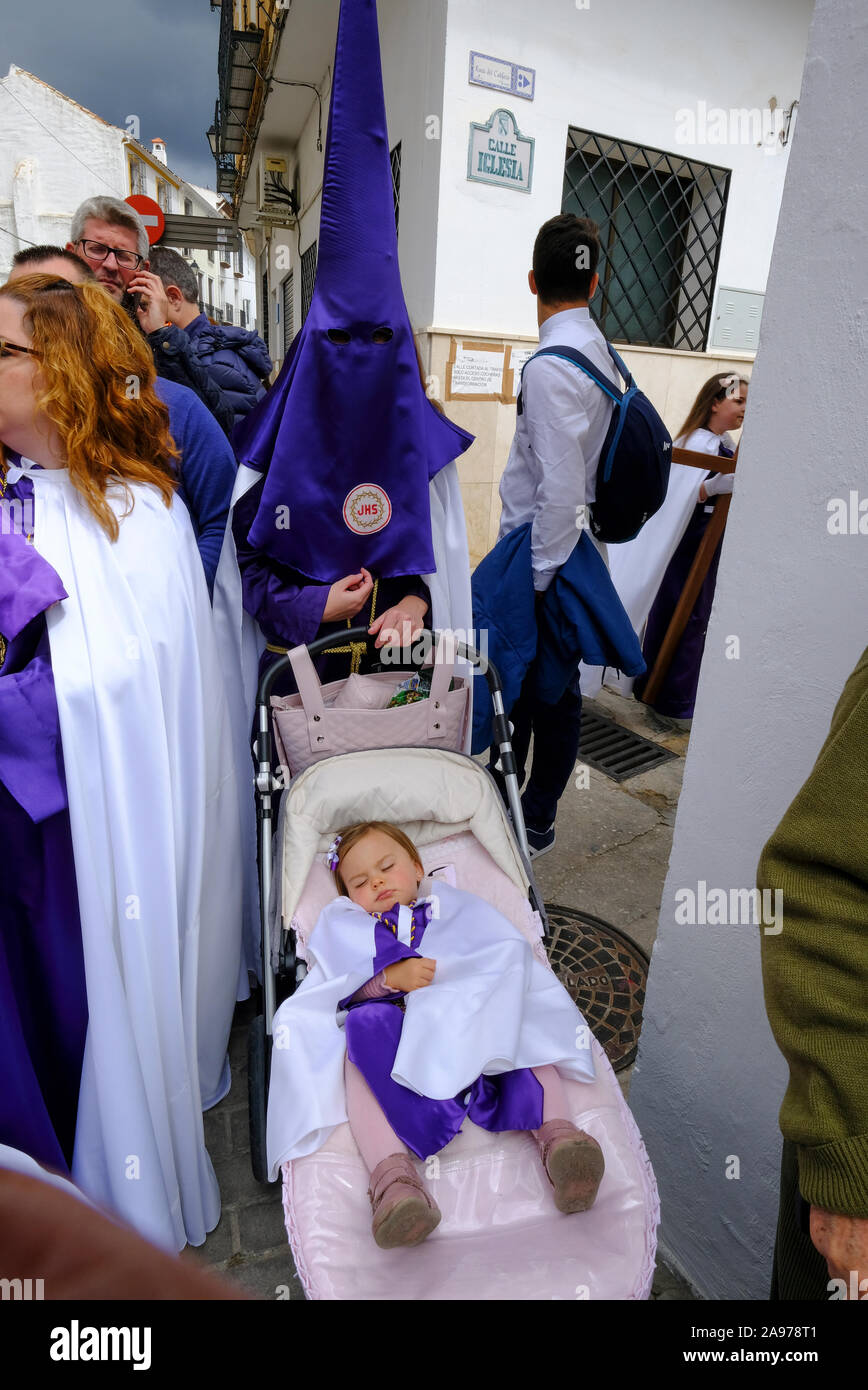 Procession of local community wearing purple capirotes, bearing Jesus and the Cross during Holy Week. Carcabuey, Cordoba Province, Andalucia. Spain Stock Photo
