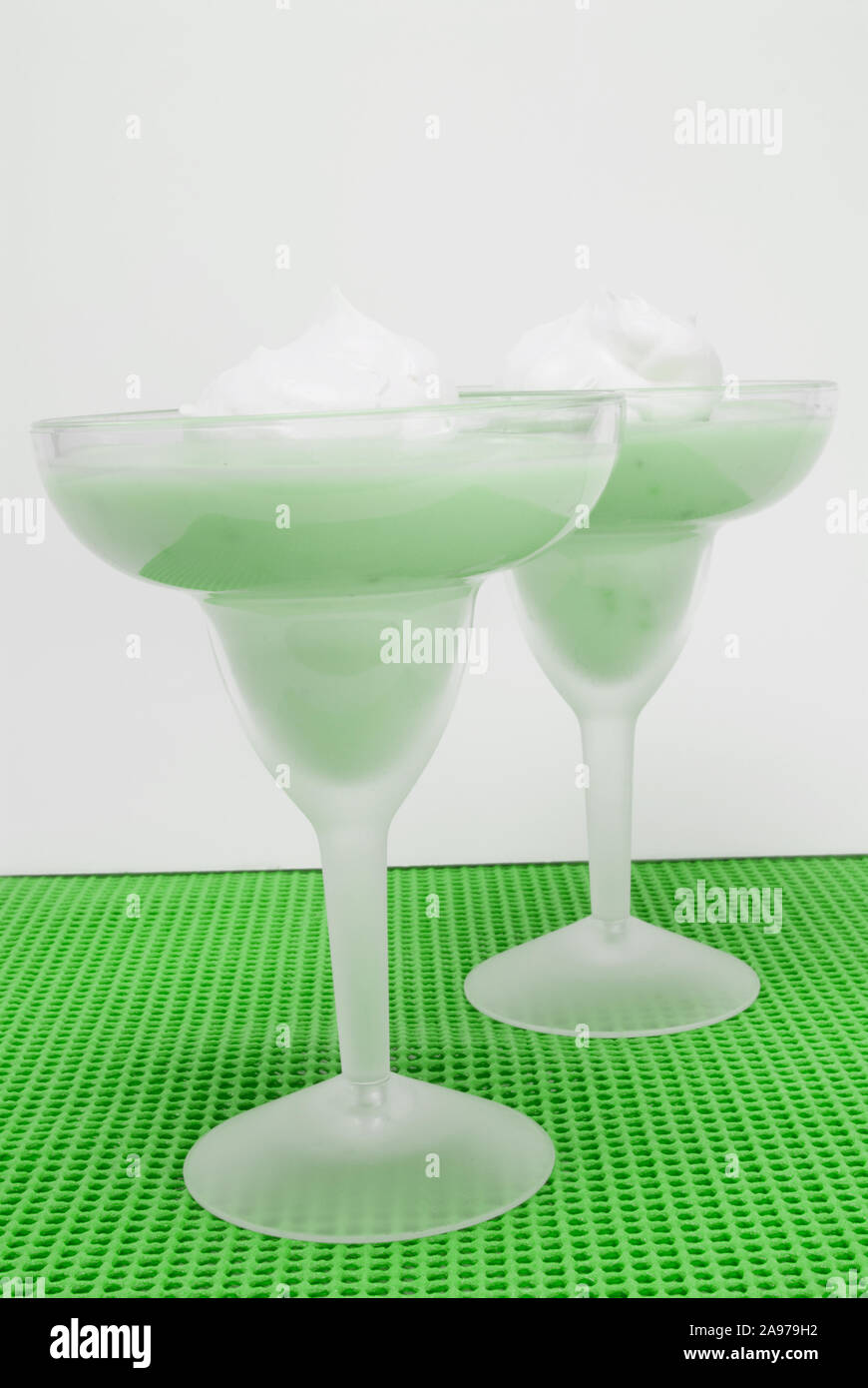 Eye level shot of homemade green colored pistachio pudding with a dollop of whipped cream on top served in two frosted margarita glasses. Naturally li Stock Photo